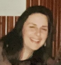 A photo of Mackenzie Newnham, the Chaplain/Spirituality & Wellbeing Practitioner at Gartnavel Hospital. She is white, with long dark hair pulled back, and is smiling.